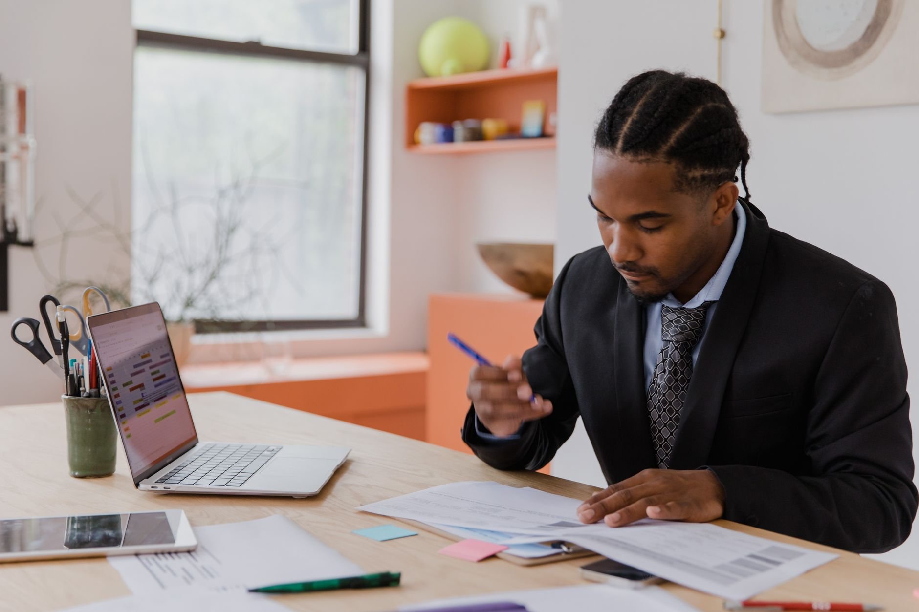 A professional businessman working at his desk, reviewing documents in a modern office environment.